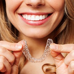 Woman smiling while holding clear aligner