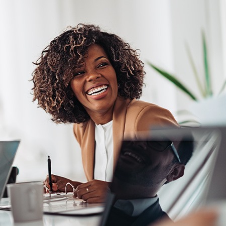 Woman smiling while taking notes during meeting