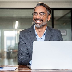 Man with glasses smiling while working in office