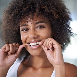 Woman smiling while flossing her teeth
