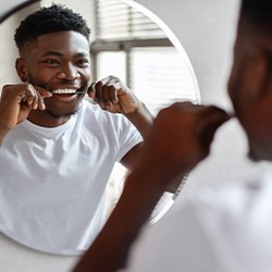 Man smiling while flossing his teeth