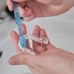 Closeup of patient cleaning clear aligner in sink