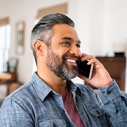 Man smiling while talking on phone at home