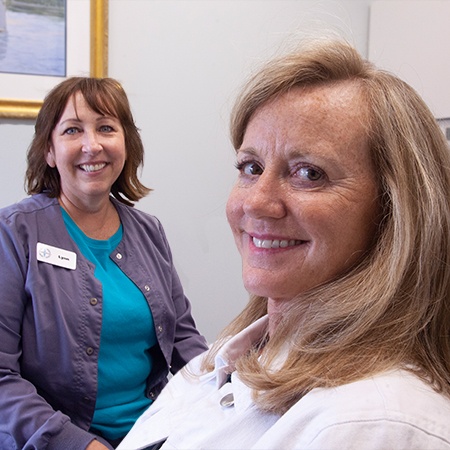 Woman in dental chair shaking hands with dentist