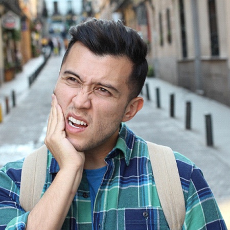 person holding their jaw in pain