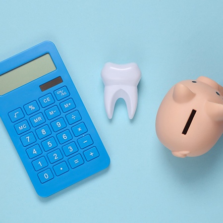  A calculator, model tooth, and piggy bank against a blue background 