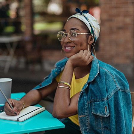 person writing in a journal at a table in a café 