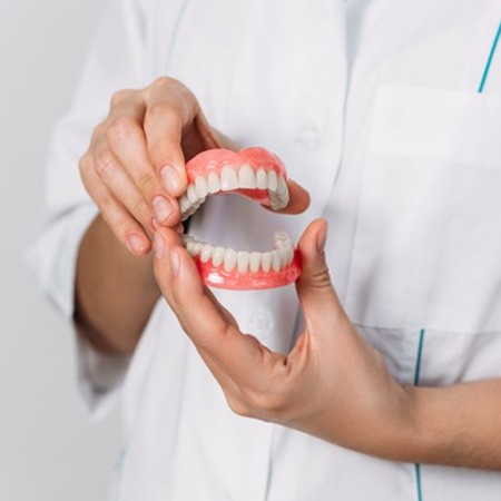 a dentist presenting a pair of new dentures