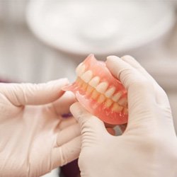 a dentist holding up a pair of dentures