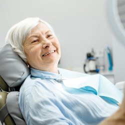 a patient checking her new dentures with a mirror