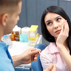 Woman at dentist’s office holding her face in pain