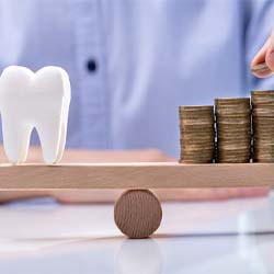 Tooth and coins balancing on a wooden scale