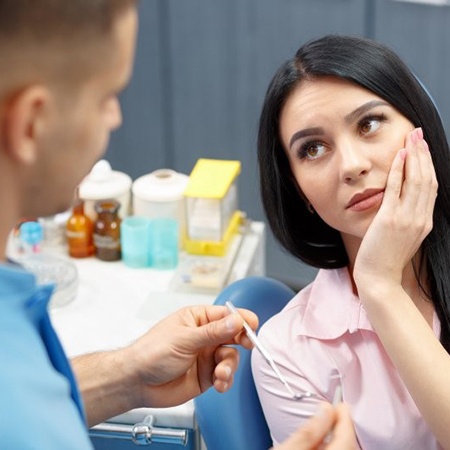 A woman with tooth pain listening to a dentist.