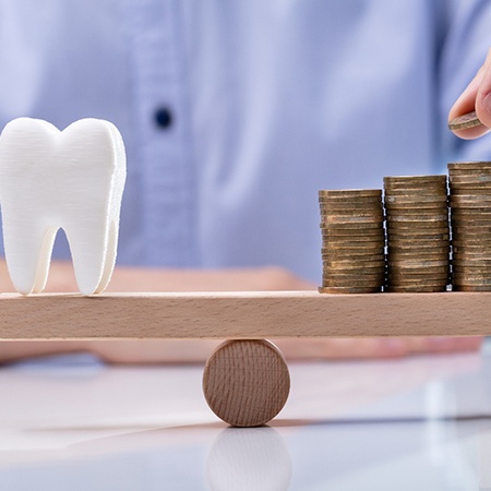 Man balancing tooth a coins on wooden scale