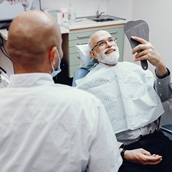dental implant patient admiring his results in a mirror