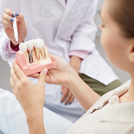 dentist showing a dental implant model to a patient