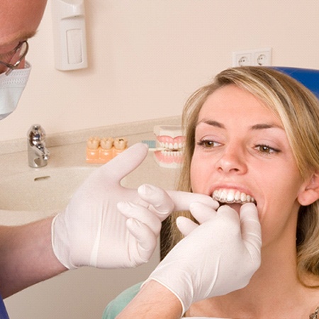 A dentist inserting an MTM clear aligner into a female patient’s mouth to ensure proper fit