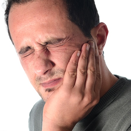 Man holding cheek in pain