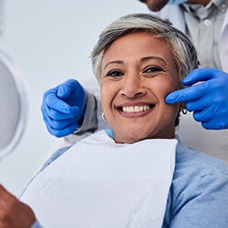 smiling woman with the dentist’s hands around her face