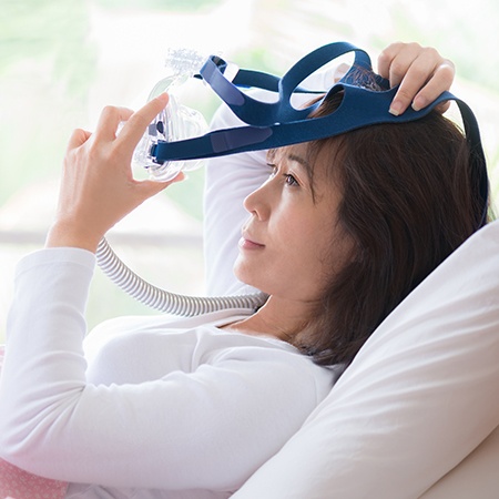 Woman putting on CPAP mask