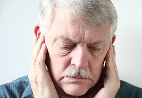 Older man holding his jaw