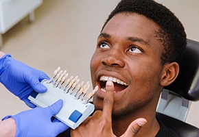 Man's smile compared with tooth color chart