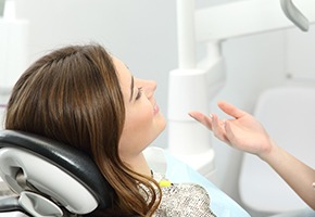 Woman in dental chair smiling at dentist