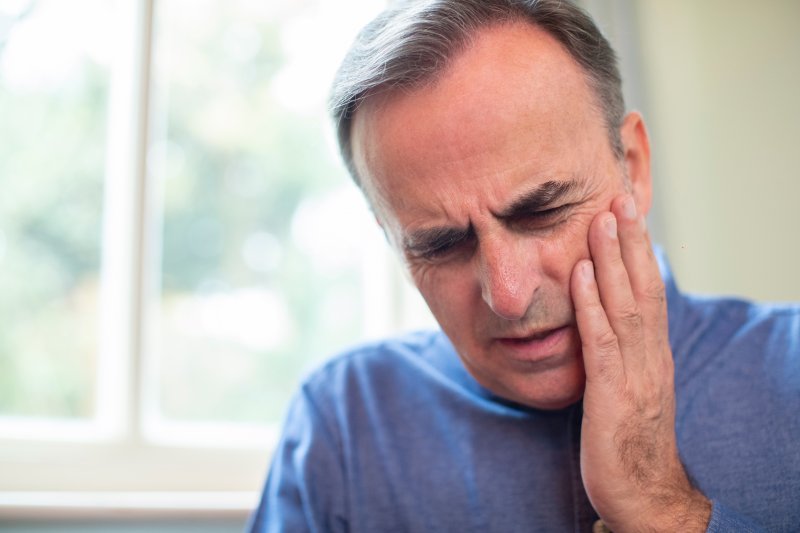 A man holding his cheek in pain.