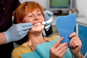 Older woman in dentist’s chair looking in a mirror