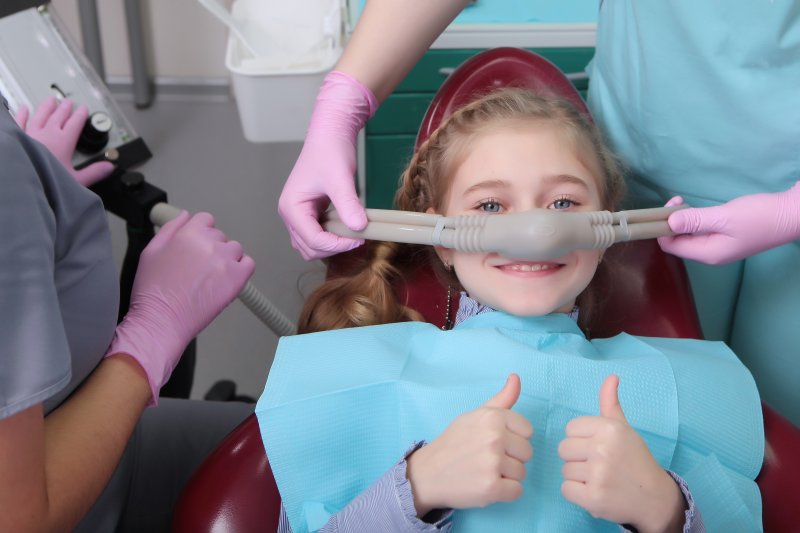 Child giving thumbs up while going through sedation dentistry
