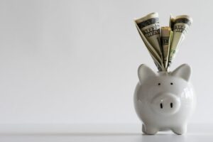 Cash stuffed into a white piggy bank.