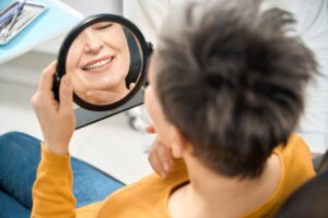 Woman looking at herself in mirror in dentist's chair.